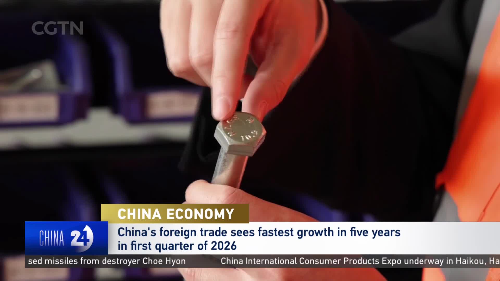 Fingers carefully examine a metal bolt, its hexagonal head glinting under the lights. This close-up view, presented by CGTN, highlights a component of China's booming economy.