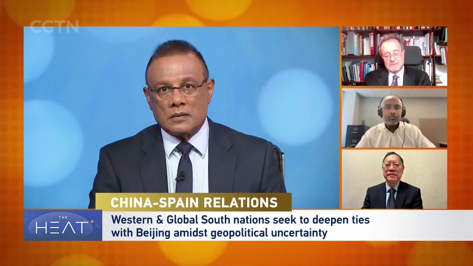 A man in a suit and tie, with glasses, looks directly forward. Three other men appear in smaller boxes on the right, also in professional attire, as a CGTN broadcast discusses China-Spain relations.