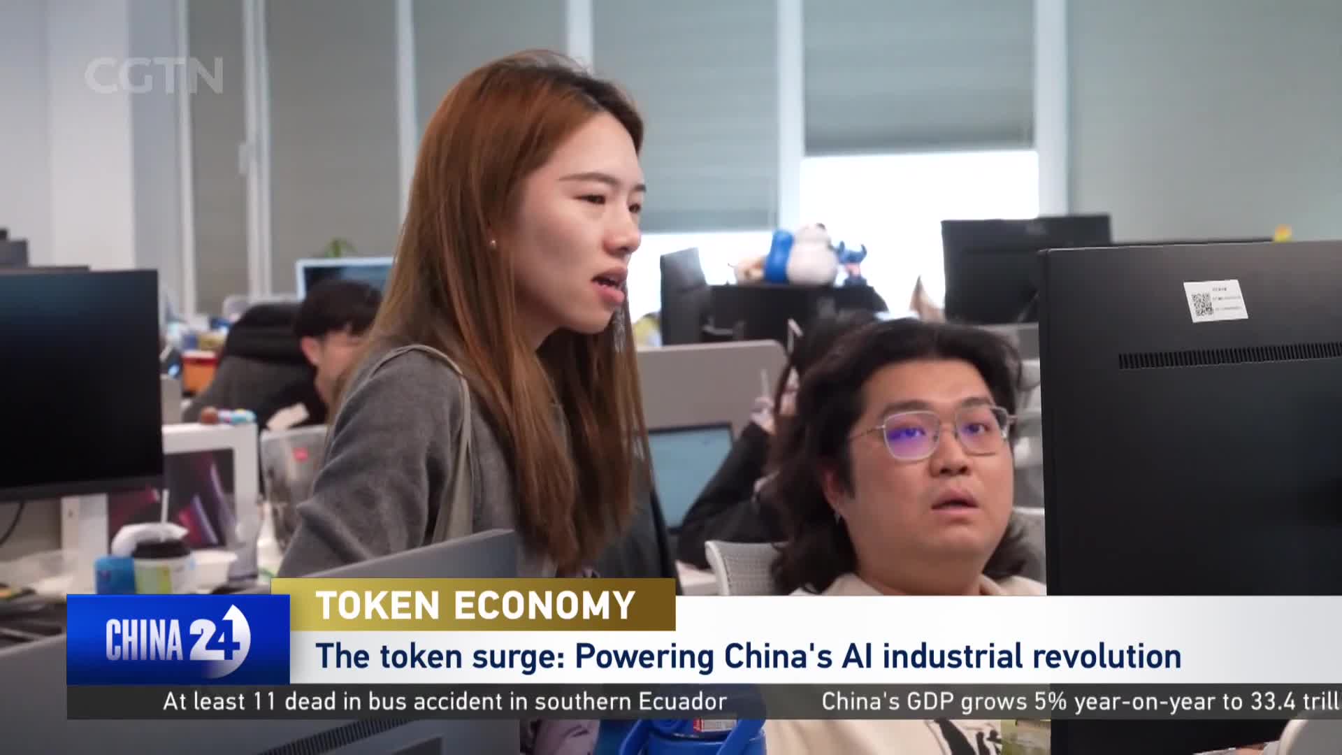 A young woman with long brown hair leans forward, speaking intently. Beside her, a man with glasses stares at a computer screen, his mouth slightly open. A CGTN graphic overlays the scene, discussing China's AI revolution.