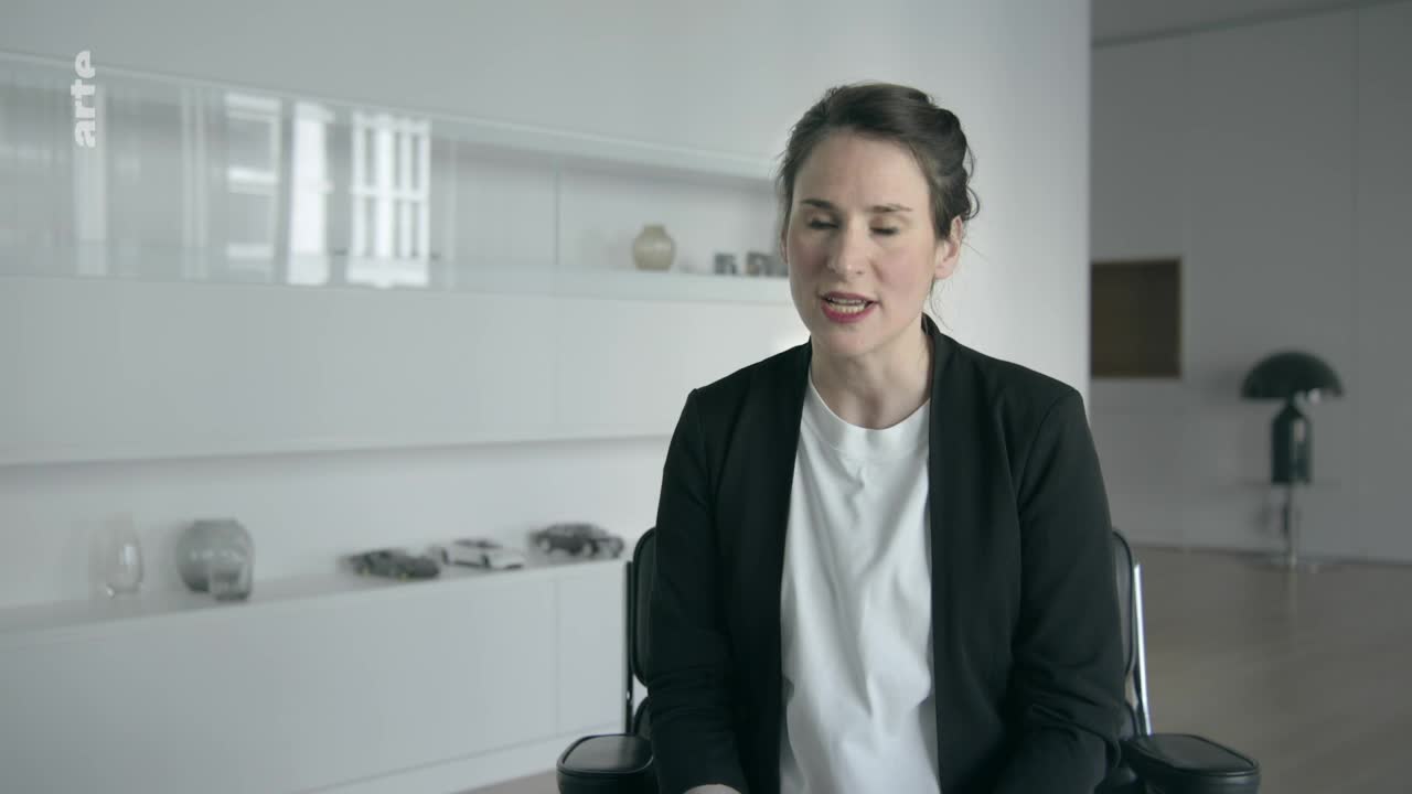 A woman in a black blazer speaks, her words forming in the air. The arte logo sits in the corner, a subtle reminder of the broadcast.
