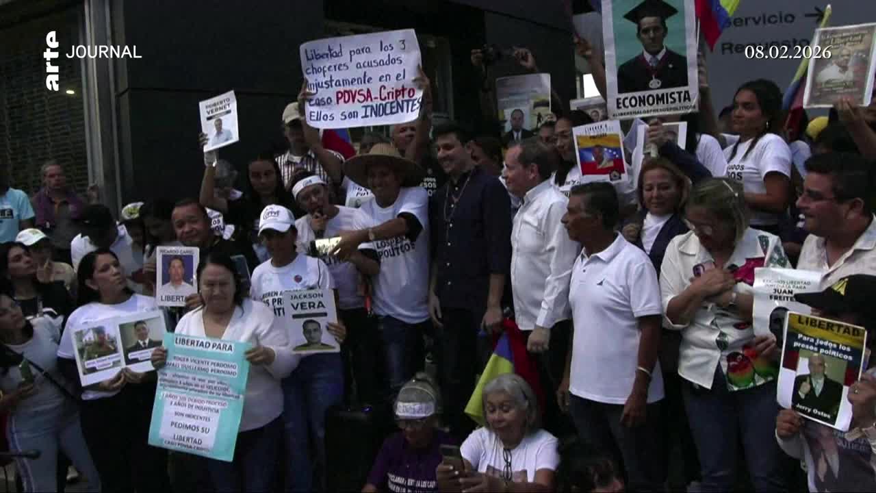 A crowd holds up signs demanding freedom for individuals. Venezuelan flags are visible among the protesters.