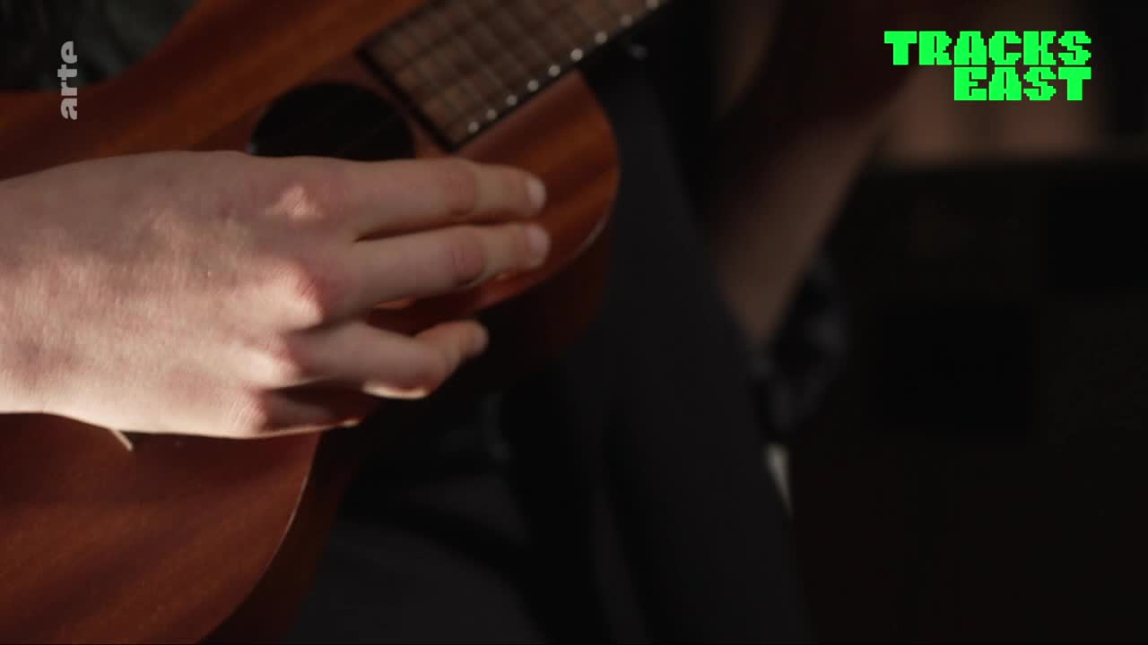 Fingers strum across the wooden ukulele, the sound of the strings a soft melody. The "arte" logo is visible in the corner, a subtle reminder of its French broadcast.