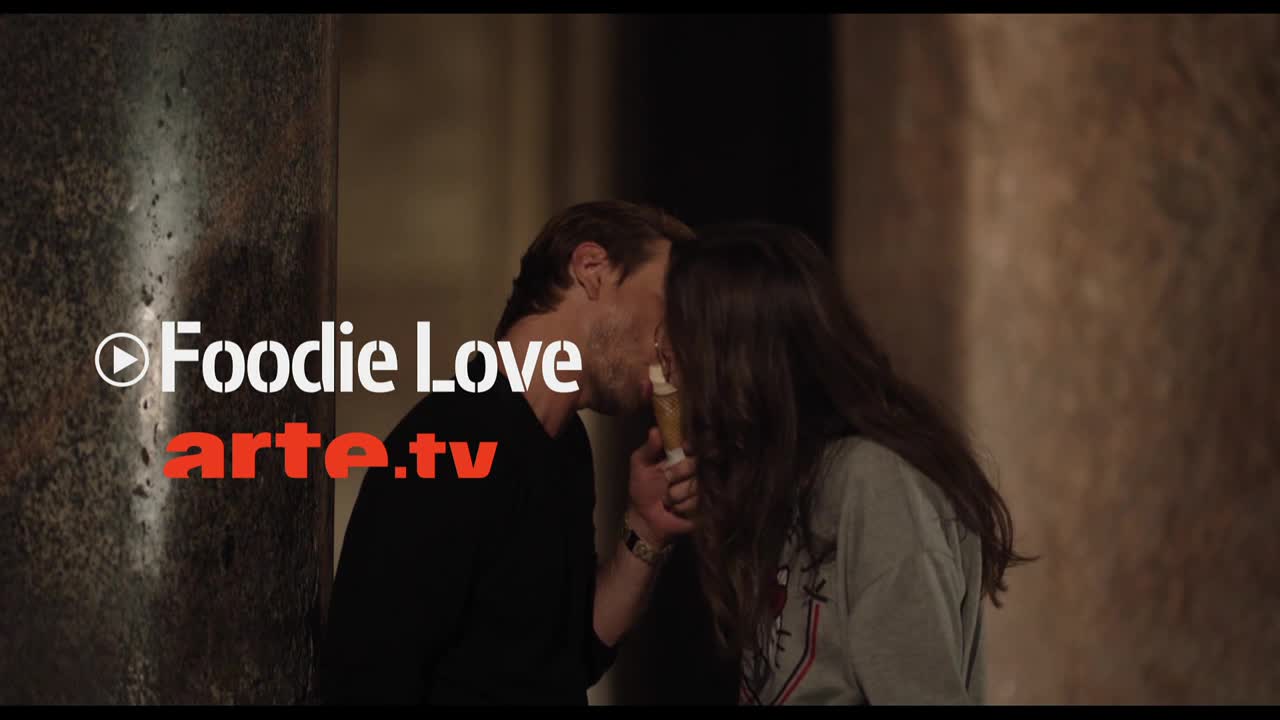 A man and woman lean in, sharing a kiss over a small, cylindrical object. The arte.tv logo is visible on the left side of the frame.