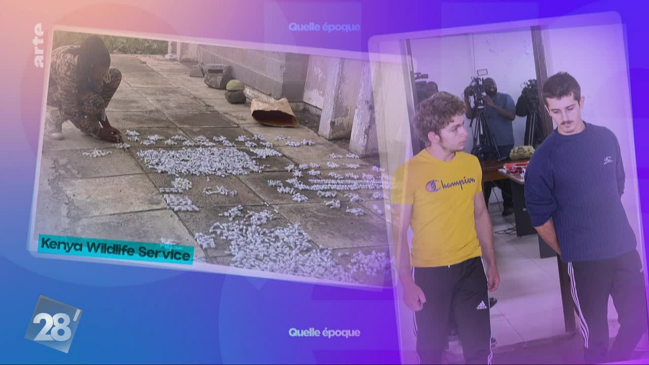 A person crouches on a tiled surface, carefully arranging small, pale objects. Two young men stand in a room, one in a yellow shirt, the other in blue, with cameras pointed at them.