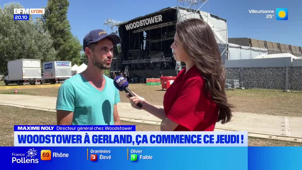 A BFM Lyon reporter holds a microphone, interviewing a man in a baseball cap in front of a stage. Behind them, a banner reads "WOODSTOWER" against a bright, sunny sky.

