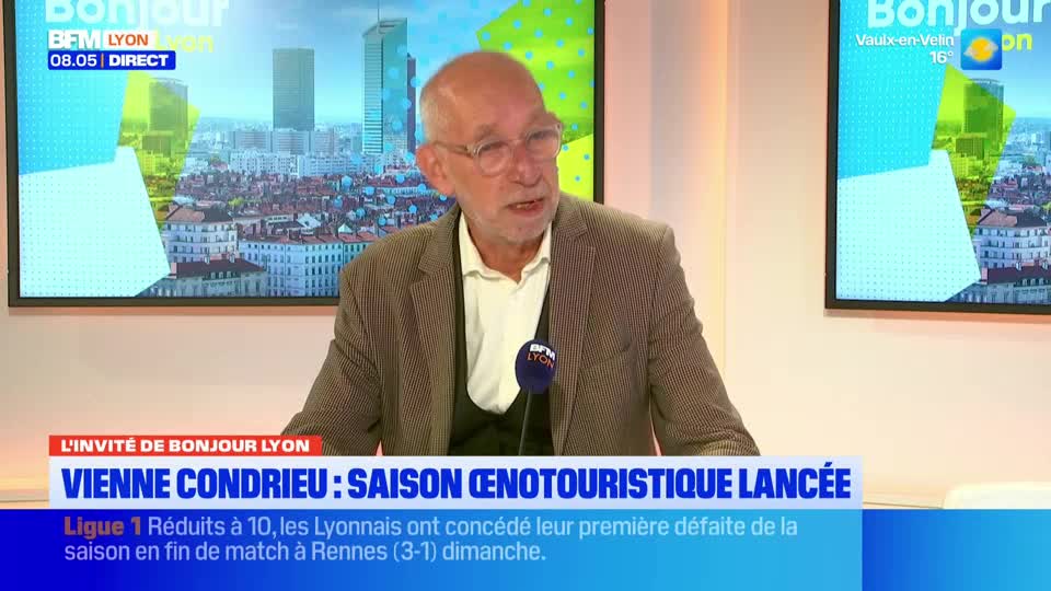 In the BFM Lyon studio, a man in glasses is speaking into a microphone, with the city skyline visible on the screen behind him. The chyron below mentions the Lyon football team's recent loss.
