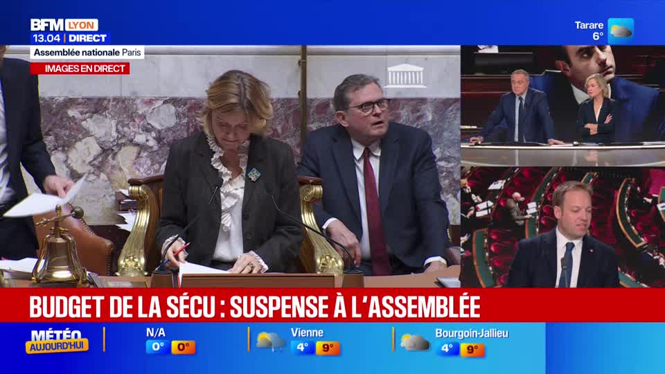 In a live broadcast from the French National Assembly, a man in a suit looks up, while a woman in a blazer reads documents. The chyron on BFM Lyon reads "Budget de la Sécu: Suspendu à l'Assemblée."
