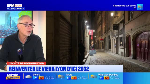 A man with glasses speaks into a microphone, his face illuminated by studio lights. Behind him, a narrow, cobblestone street in Lyon glows under the dim evening light, with shuttered shops lining its sides. A man with glasses speaks into a microphone, his face illuminated by studio lights. Behind him, a narrow, cobblestone street in Lyon glows under the dim evening light, with shuttered shops lining its sides.
