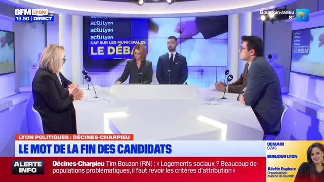 Four people are seated at a white table in a studio, facing microphones. A screen behind them displays "LE DÉBAT" in large blue letters. A news ticker at the bottom of the screen reads "LYON POLITIQUES: DÉCINES-CHARPIEU LE MOT DE LA FIN DES CANDIDATS." Four people are seated at a white table in a studio, facing microphones. A screen behind them displays "LE DÉBAT" in large blue letters. A news ticker at the bottom of the screen reads "LYON POLITIQUES: DÉCINES-CHARPIEU LE MOT DE LA FIN DES CANDIDATS."
