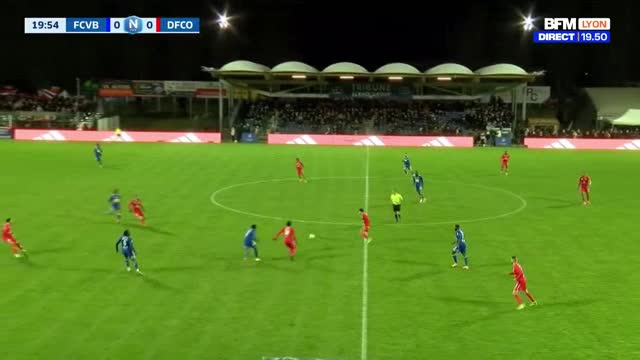 A player in red sprints down the wing, looking to make a pass. Another player in blue closes in on him, attempting to intercept. The scoreboard shows FCVB and DFCO are tied at zero. A player in red sprints down the wing, looking to make a pass. Another player in blue closes in on him, attempting to intercept. The scoreboard shows FCVB and DFCO are tied at zero.