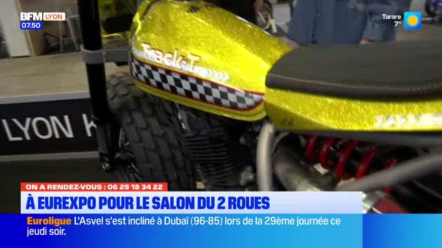 A custom motorcycle with a glittery yellow tank and a checkered stripe sits on display at the Salon du 2 Roues in Eurexpo, Lyon. Red suspension springs are visible beneath the seat. A custom motorcycle with a glittery yellow tank and a checkered stripe sits on display at the Salon du 2 Roues in Eurexpo, Lyon. Red suspension springs are visible beneath the seat.