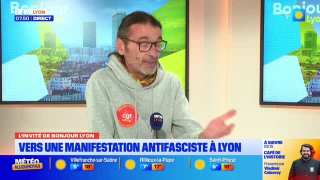 A man in a grey hoodie with a CGT badge speaks into a microphone. He gestures with his right hand as a graphic behind him displays "Bonjour Lyon" and weather information. A man in a grey hoodie with a CGT badge speaks into a microphone. He gestures with his right hand as a graphic behind him displays "Bonjour Lyon" and weather information.