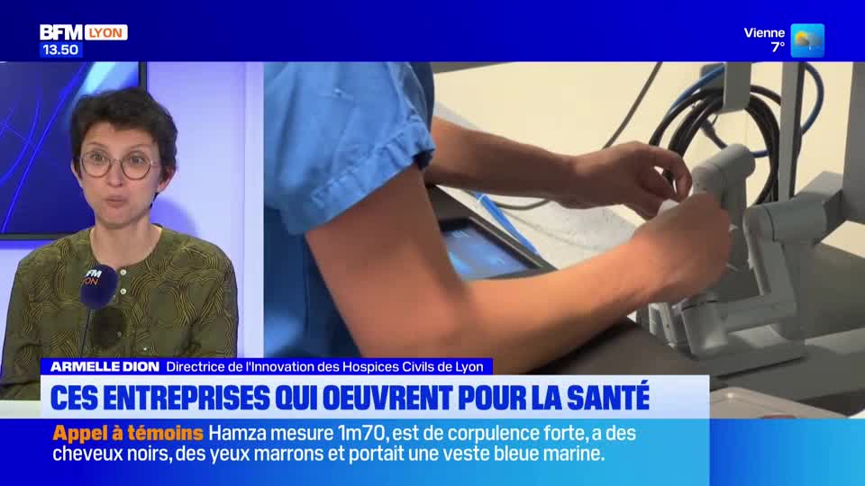 A person in blue scrubs manipulates a robotic surgical instrument. On the left, a woman with glasses speaks into a microphone.