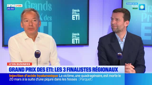 Two men sit at a table, one in a white shirt, the other in a dark suit. A screen behind them displays "Grands Prix des ETI."