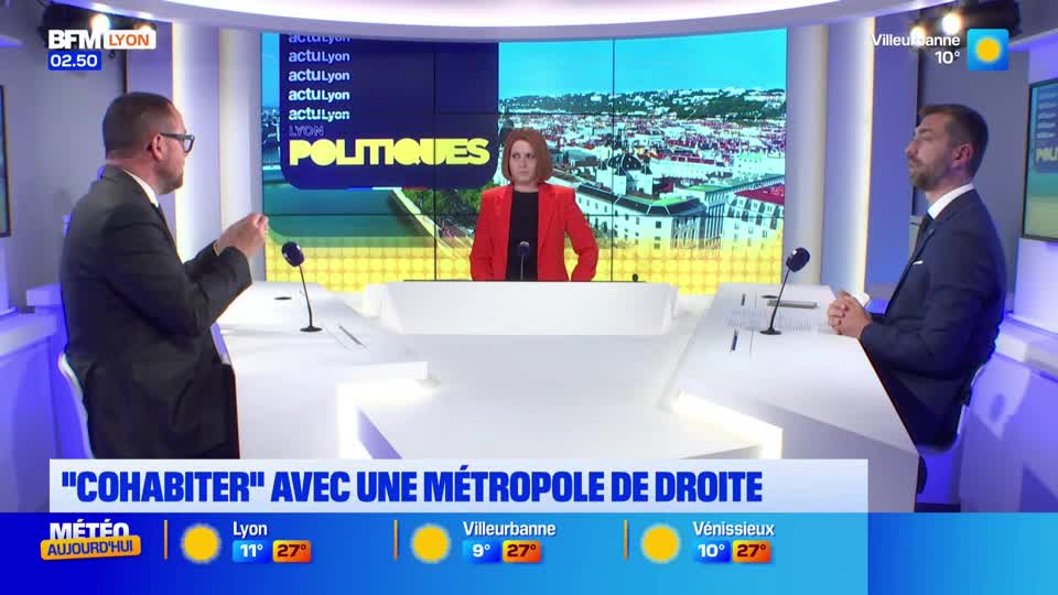 A man in a suit gestures animatedly while speaking into a microphone. Across from him, another man in a suit sits with his hands clasped, listening intently. Between them, a woman in a bright red jacket stands behind a desk, her gaze fixed forward. The BFM Lyon logo is visible in the corner, and a graphic displays "POLITIQUES" above a cityscape. A man in a suit gestures animatedly while speaking into a microphone. Across from him, another man in a suit sits with his hands clasped, listening intently. Between them, a woman in a bright red jacket stands behind a desk, her gaze fixed forward. The BFM Lyon logo is visible in the corner, and a graphic displays "POLITIQUES" above a cityscape.