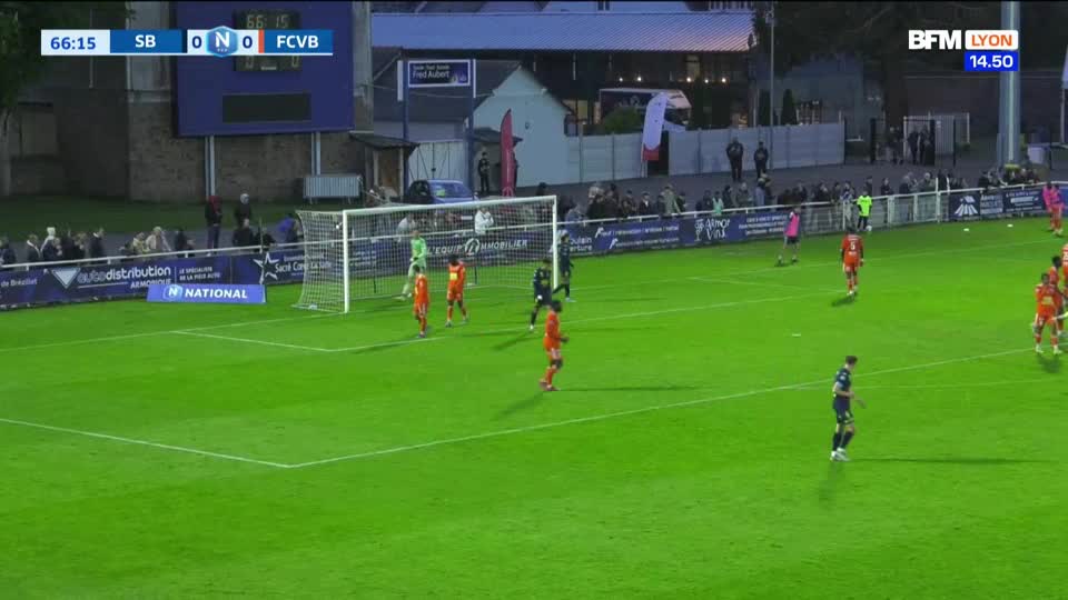 A player in a dark blue kit dribbles the ball upfield.  Several players in orange shirts are positioned near the goal, anticipating a pass.