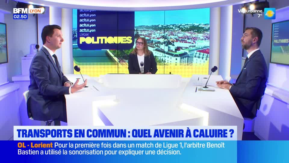 Two men in suits sit at a desk, facing each other, while a woman sits behind them. A graphic at the bottom of the screen reads "TRANSPORTS EN COMMUN : QUEL AVENIR À CALUIRE ?" Two men in suits sit at a desk, facing each other, while a woman sits behind them. A graphic at the bottom of the screen reads "TRANSPORTS EN COMMUN : QUEL AVENIR À CALUIRE ?"