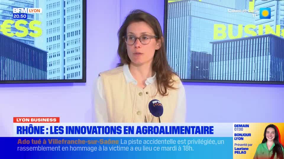 A woman with glasses speaks into a microphone, her BFM Lyon backdrop displaying "BUSINESS." Below, a headline announces "RHÔNE: LES INNOVATIONS EN AGROALIMENTAIRE," with a smaller text detailing a fatal accident in Villefranche-sur-Saône.