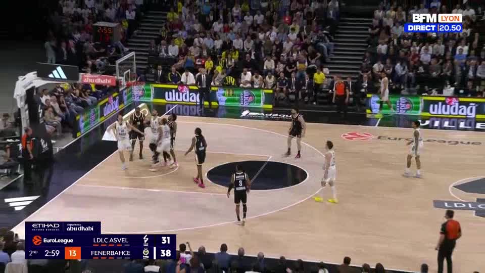 A basketball player in a black jersey with the number 3 on his back walks away from the basket. The score on the BFM Lyon broadcast shows LDLC ASVEL trailing Fenerbahçe 31 to 38.