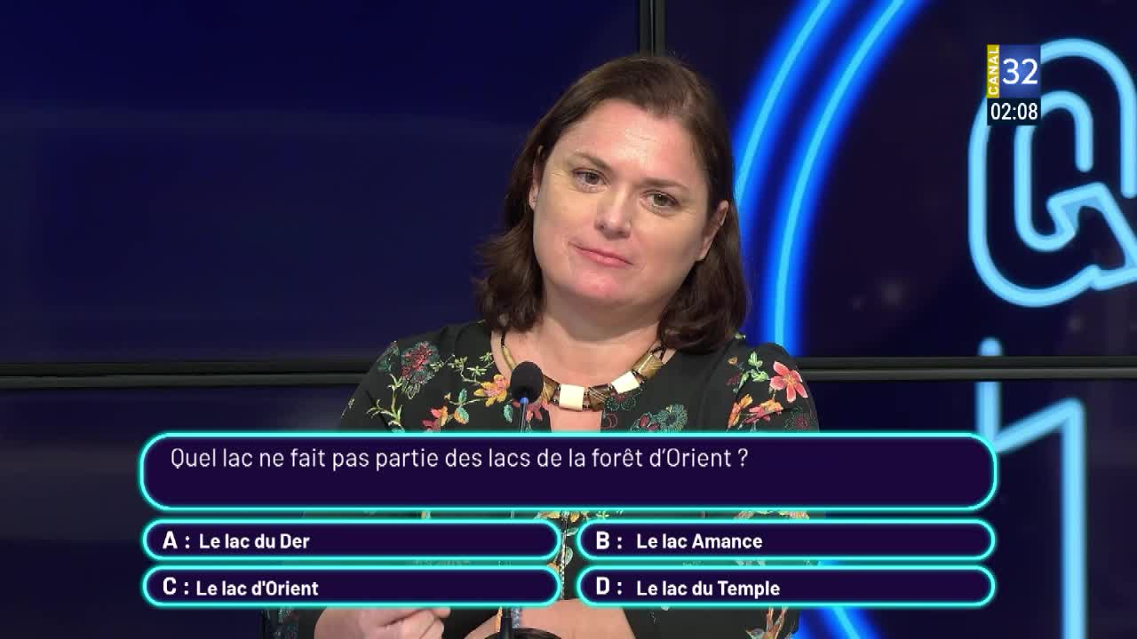 A woman on Canal 32 in France looks directly at the camera, a question about lakes in the forest of Orient displayed below her. The clock reads 02:08, and the show's logo is visible in the corner.
