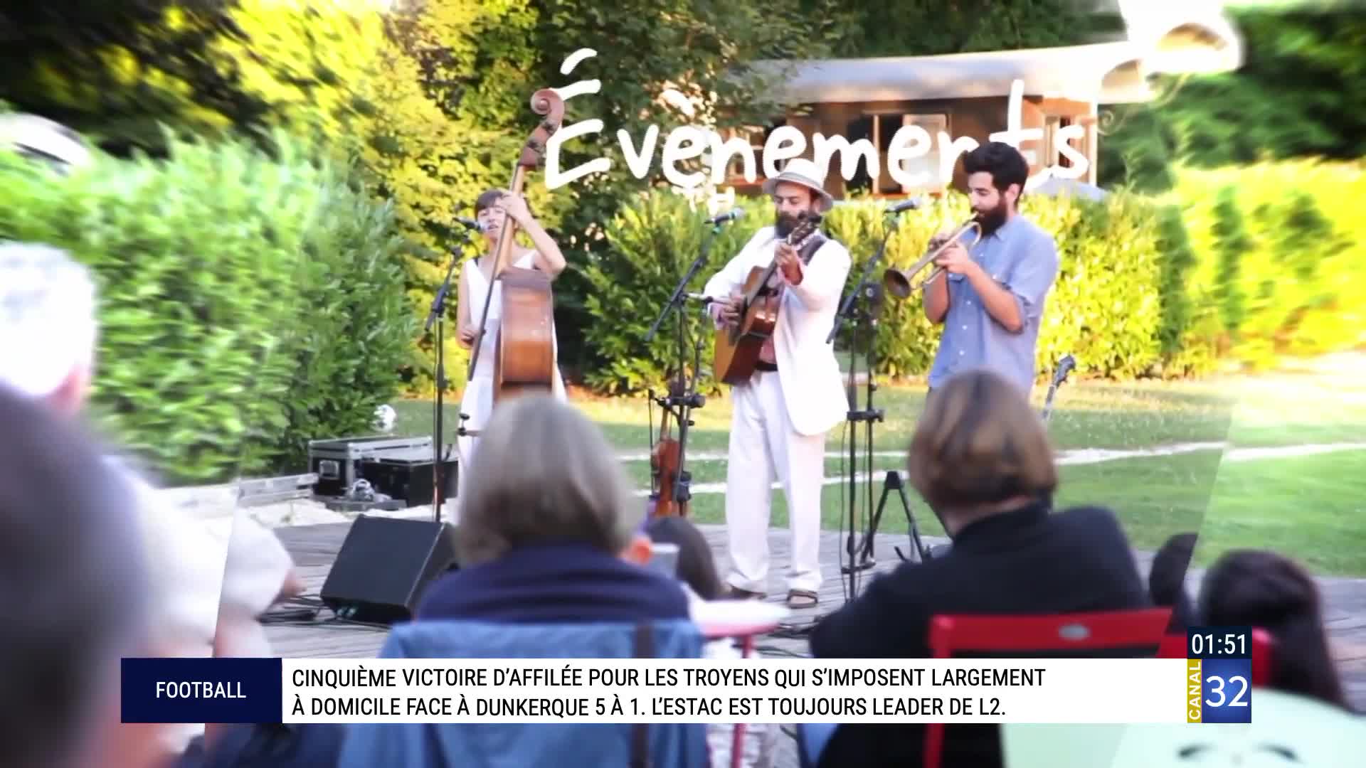 A trio plays music outdoors, with a double bass player, a guitarist, and a trumpeter. The Canal 32 graphic overlays the scene, indicating a broadcast from France. A trio plays music outdoors, with a double bass player, a guitarist, and a trumpeter. The Canal 32 graphic overlays the scene, indicating a broadcast from France.