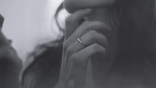 A hand, adorned with a ring, gently touches a person's neck. The other person's face is obscured, but their presence is felt.
