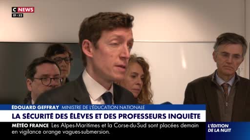 Édouard Geoffray, the Minister of National Education, speaks intently. Behind him, several people stand, their faces a mix of concern and attention.