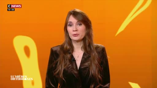 A woman with long, brown hair stands before an orange backdrop, speaking into a microphone. The CNews logo appears in the upper left corner, with the time 13:52 displayed beneath it.