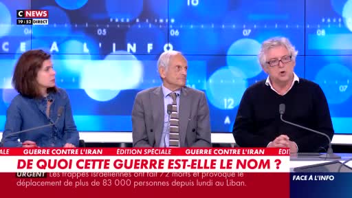 A woman in a denim shirt speaks, facing left. To her right, a man in a suit and tie looks forward, while another man with glasses, wearing a dark sweater, gestures with his hands. They are seated at a desk with a C News logo visible.