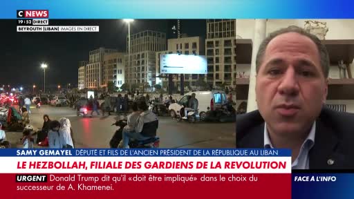 Motorbikes weave through a busy street in Beirut at night, their headlights cutting through the darkness. People gather on the sidewalks, illuminated by the glow of streetlights and building facades.