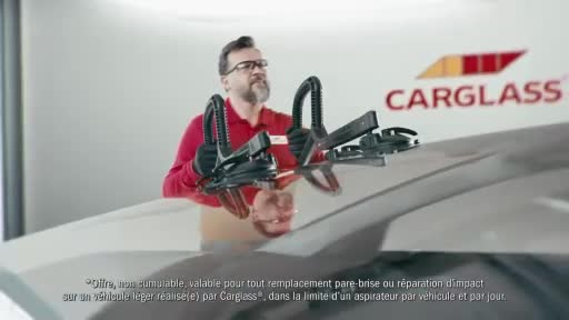 A man in a red shirt is attaching suction cups to a car's windshield. The Carglass logo is visible behind him. A man in a red shirt is attaching suction cups to a car's windshield. The Carglass logo is visible behind him.