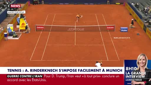 A tennis player in white is mid-swing on a clay court, about to hit the ball. Another player stands near the net, ready for the return. A tennis player in white is mid-swing on a clay court, about to hit the ball. Another player stands near the net, ready for the return.