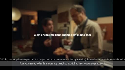 Two men stand in a kitchen, one holding a plate of food. Text overlays the scene, stating, "It's even better when it's cheaper." Two men stand in a kitchen, one holding a plate of food. Text overlays the scene, stating, "It's even better when it's cheaper."