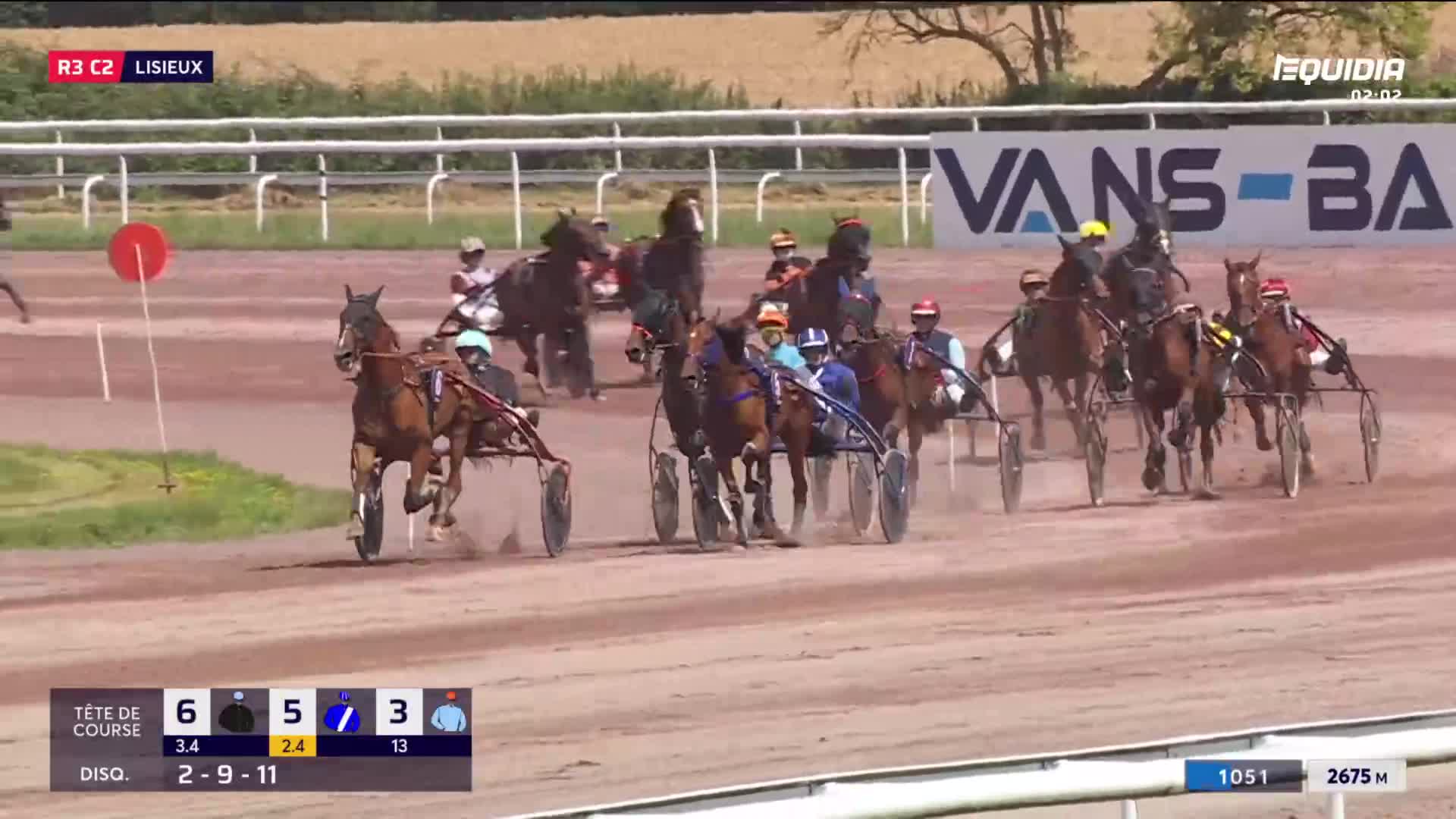 Harness racing is underway at Lisieux, France, with the horses and sulkies bunched together on the track. The Equidia broadcast shows the race is in progress, with the lead horse, number 6, pulling ahead.
