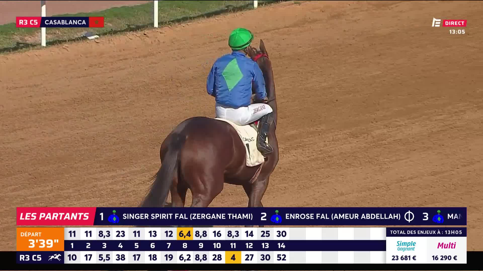 A jockey in blue and green sits atop a brown horse, facing away from the camera. The Equidia broadcast shows the race is in Casablanca.
