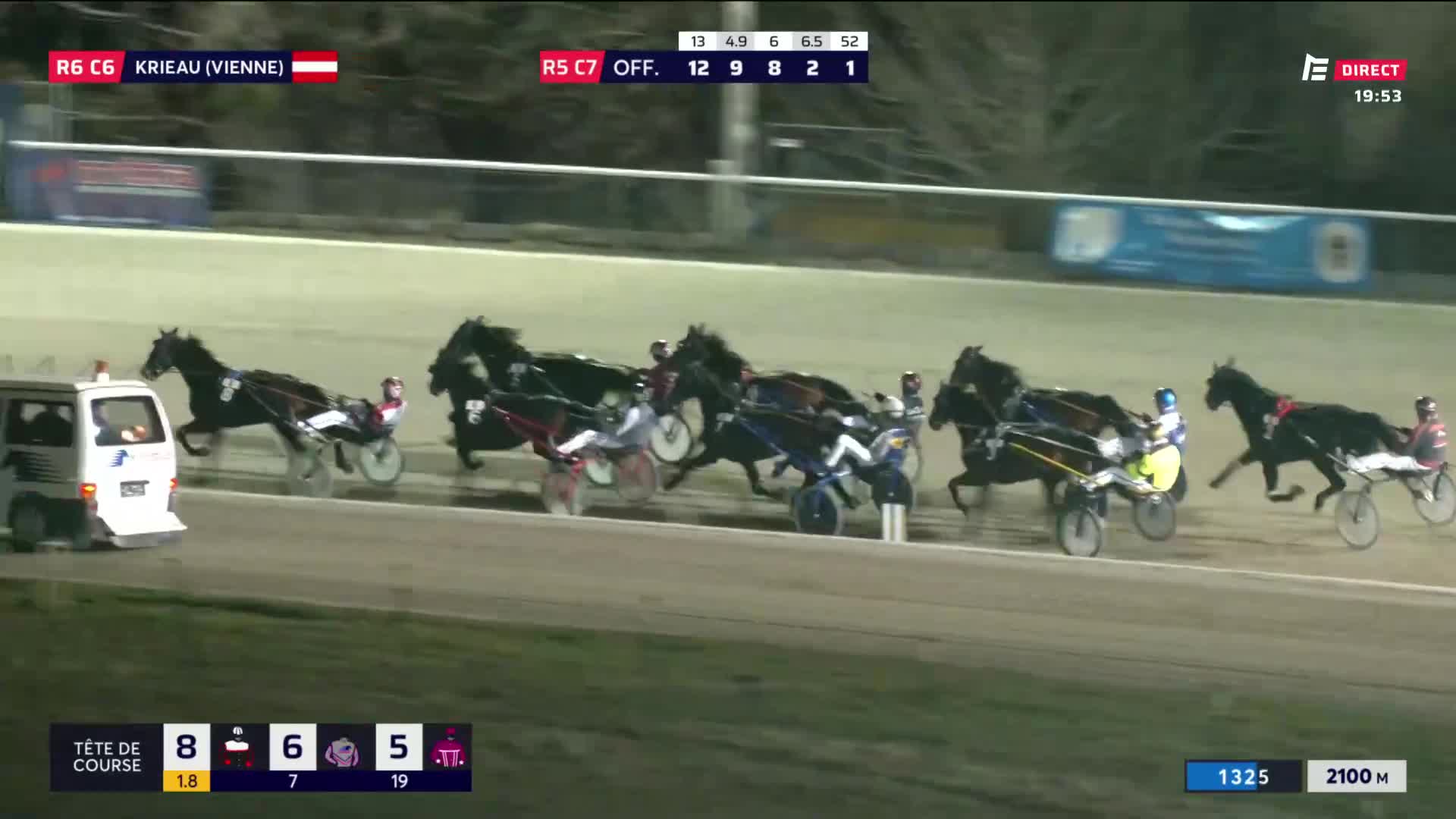 The horses are thundering down the track, their sulkies kicking up dust. A white van follows closely behind, its lights flashing. The horses are thundering down the track, their sulkies kicking up dust. A white van follows closely behind, its lights flashing.