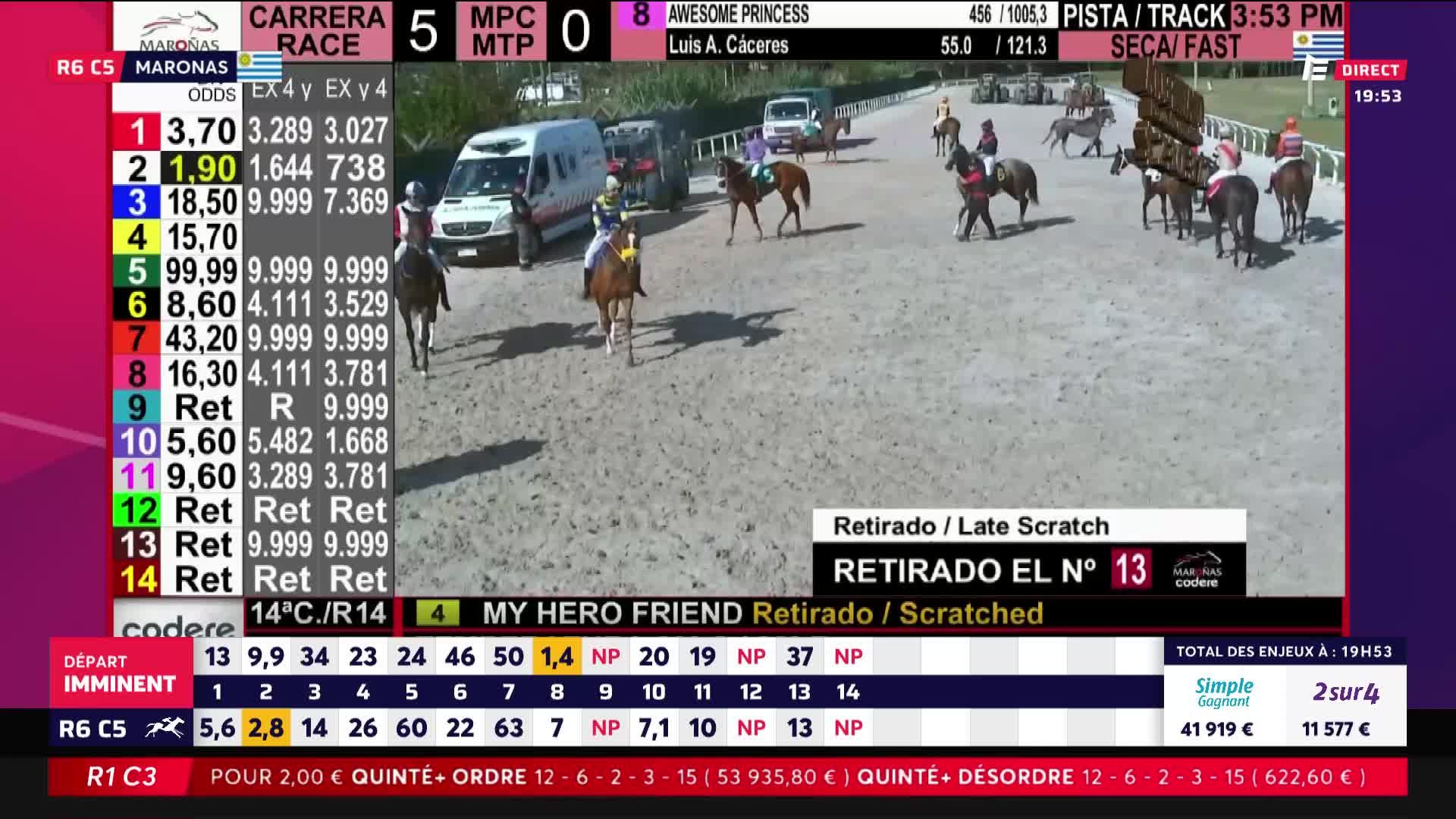 A horse and rider in yellow and blue silks trots past, their mount's ears pricked forward. Another horse, this one with a jockey in red and white, canters further down the track, its rider leaning low.