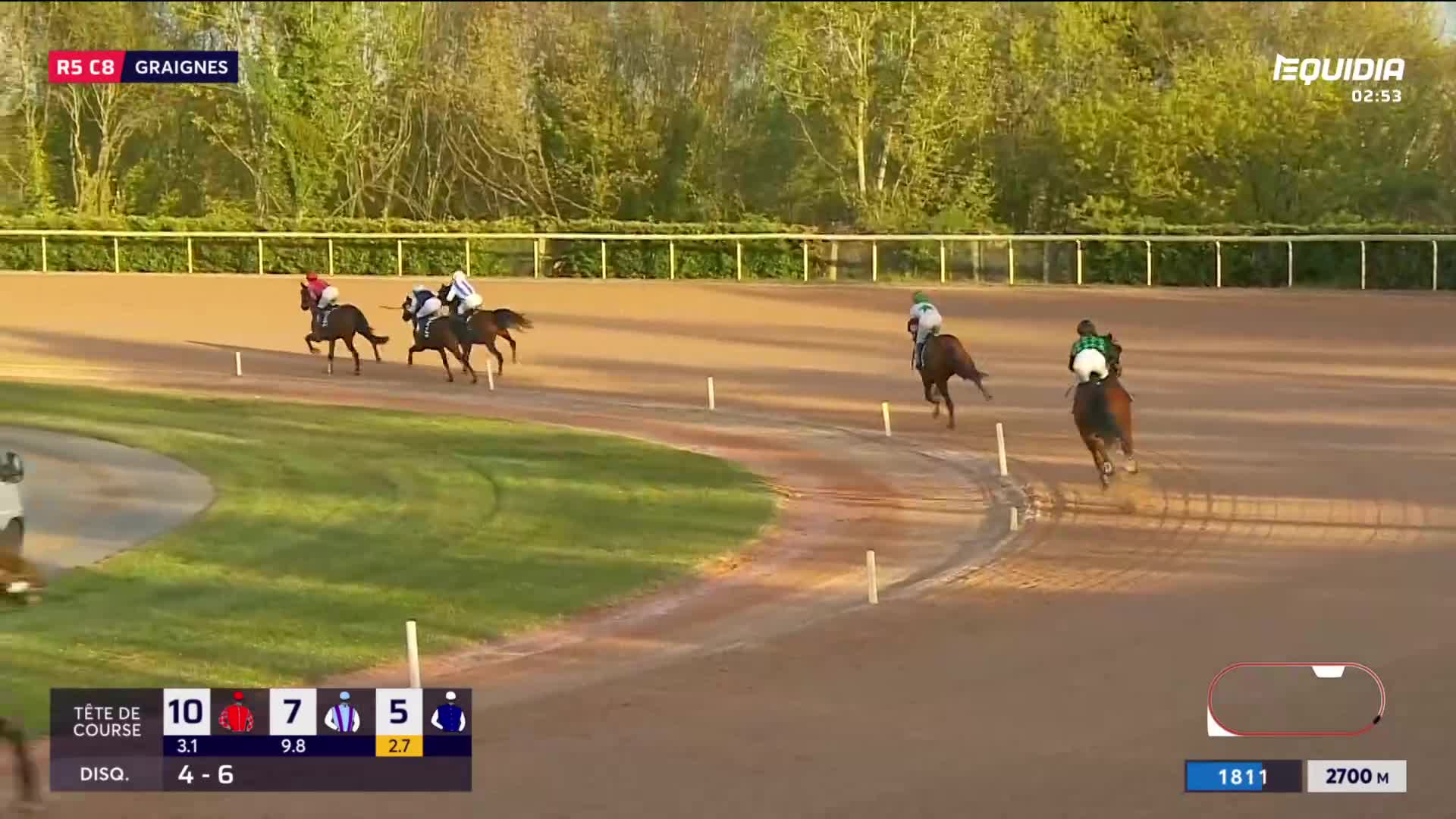 The horses are thundering down the dirt track, their riders hunched low. One horse, with a jockey in green, pulls ahead on the outside. The horses are thundering down the dirt track, their riders hunched low. One horse, with a jockey in green, pulls ahead on the outside.