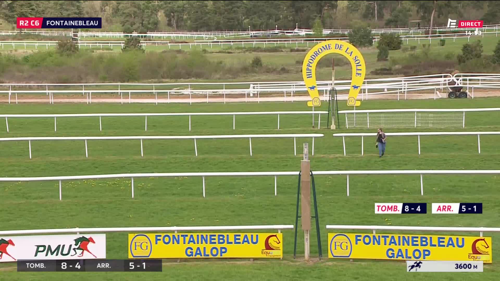 A lone figure walks across the grassy track at Hippodrome de la Solle, past the iconic yellow horseshoe arch. The green expanse of the racecourse stretches out, marked by white rails, under a bright sky. A lone figure walks across the grassy track at Hippodrome de la Solle, past the iconic yellow horseshoe arch. The green expanse of the racecourse stretches out, marked by white rails, under a bright sky.