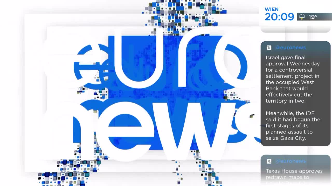 The Euronews logo, a bold blue and white design, dominates the screen. News headlines and the time in Vienna are displayed next to it.
