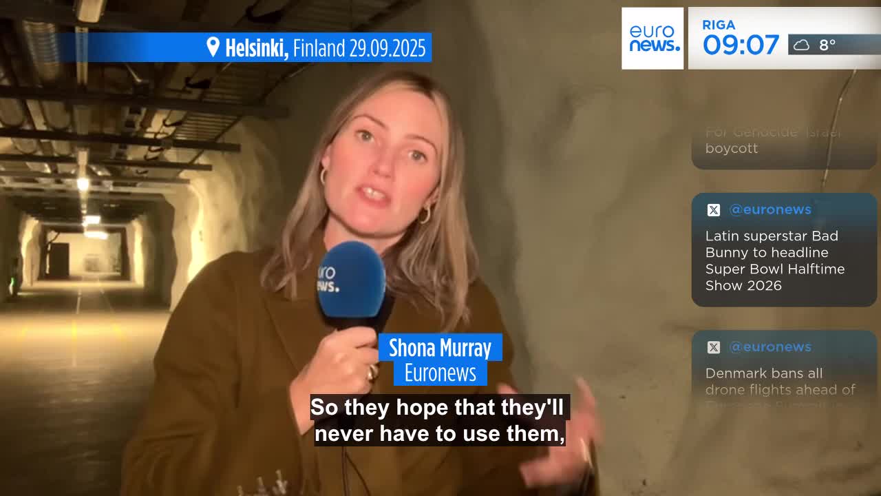 A Euronews reporter is speaking into a microphone, standing in a long, concrete tunnel. Behind her, the tunnel stretches into the distance, illuminated by evenly spaced lights.
