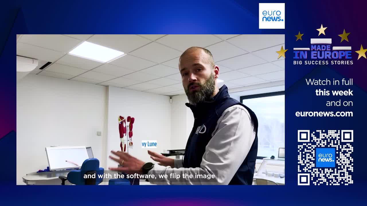A man with a beard gestures towards a screen, explaining something about flipping an image. A model of human legs stands on a table behind him.