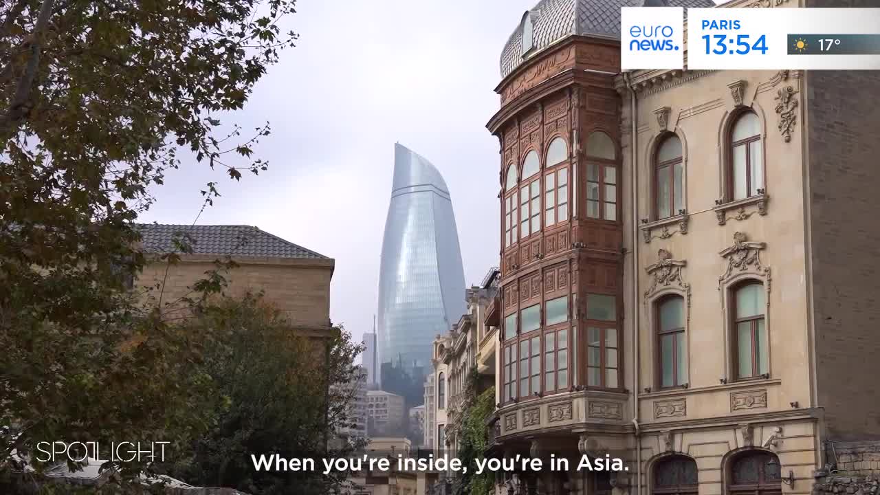 The flame-shaped Flame Towers pierce the sky behind an ornate, older building. A subtle overlay from Euronews English indicates the time in Paris.