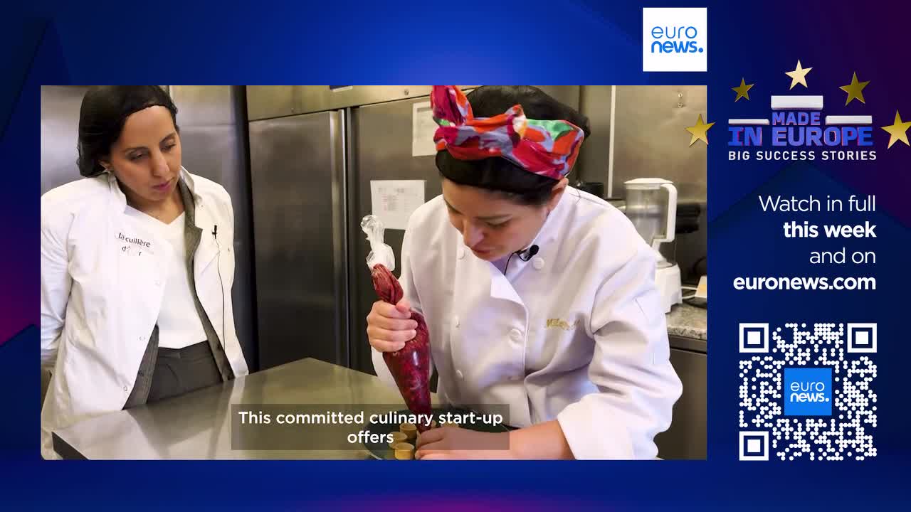 A chef carefully pipes a rich red filling onto small, round pastries. Another woman in a chef's coat watches intently, her gaze fixed on the delicate work.