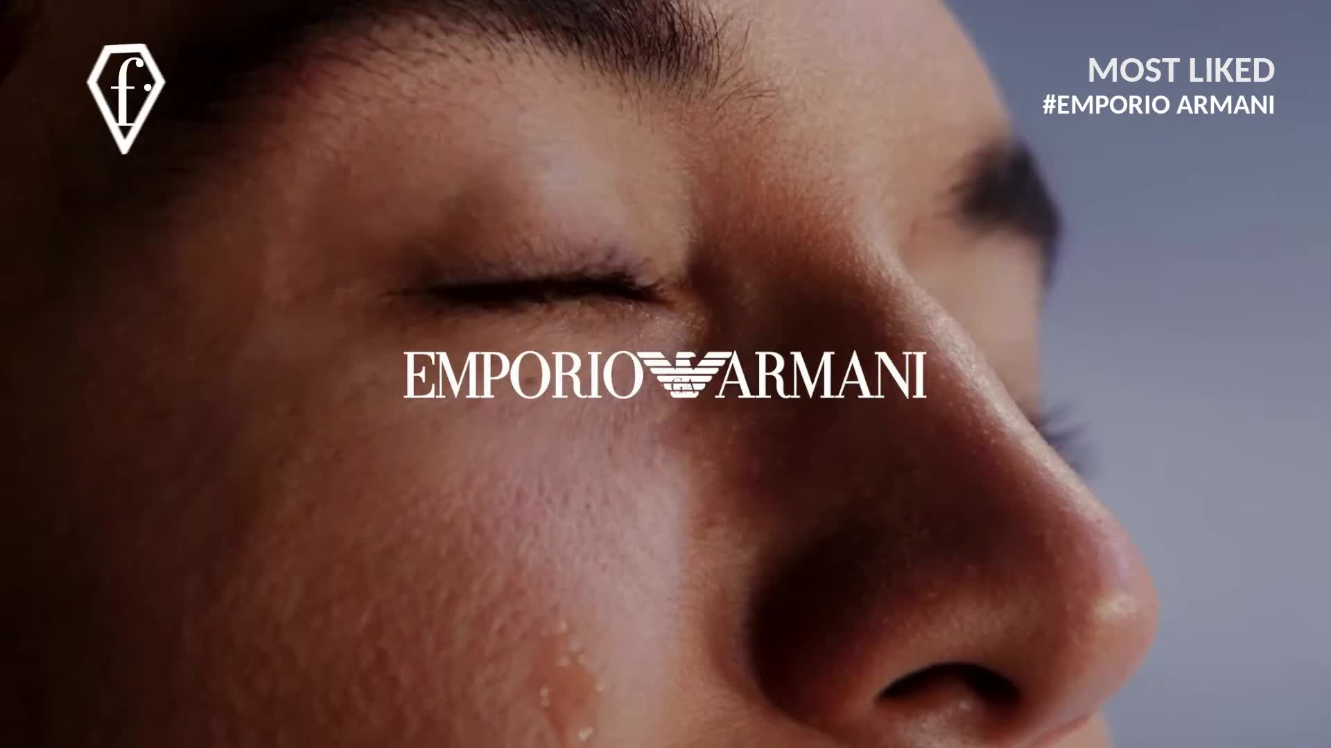 A tear slowly rolls down a cheek, reflecting the light. The closed eyes and the Emporio Armani logo suggest a moment of intense emotion, perhaps from a FashionTV Europe commercial.
