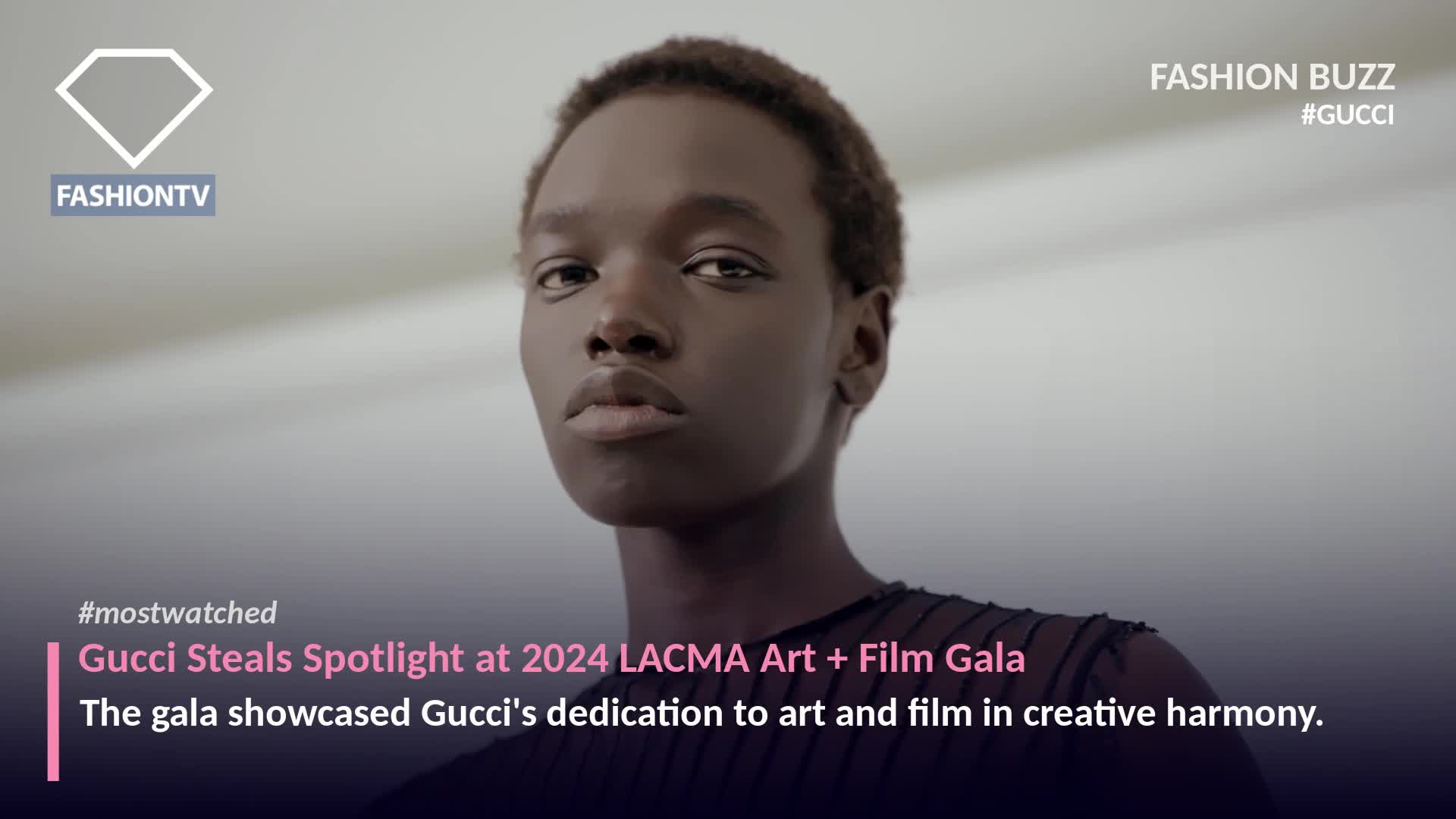 A young person gazes directly at the camera, their dark skin contrasting with the bright background. The FashionTV logo and Gucci's name are prominently displayed, hinting at a high-fashion event.
