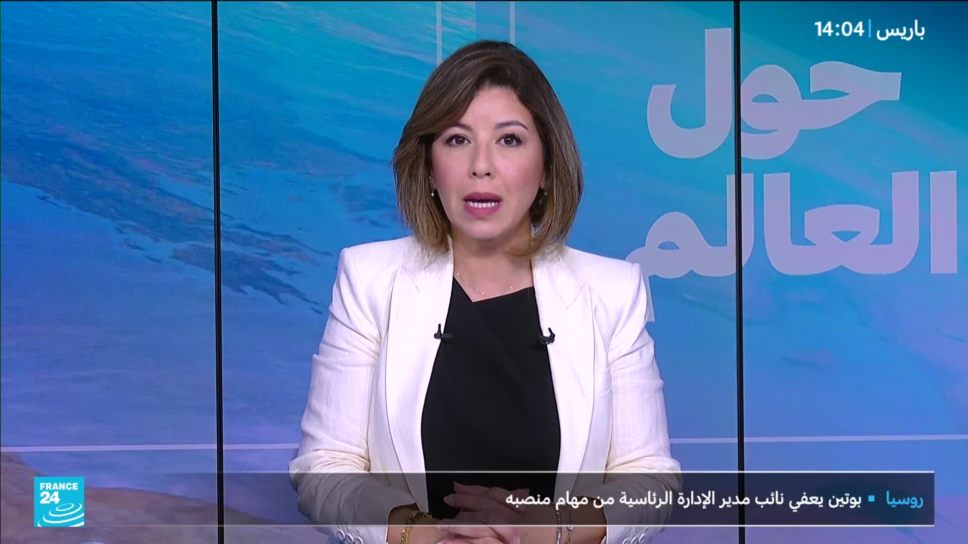 A woman in a white blazer and black top is speaking directly to the camera, framed by a blue backdrop and the France 24 logo. The time in Paris is displayed at the top of the screen, and Arabic script is visible behind her.
