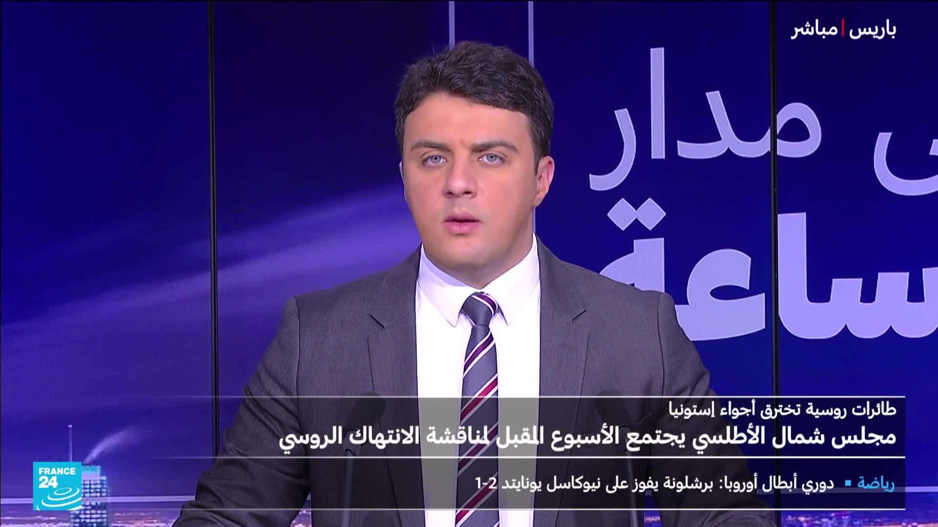 A man in a suit and tie, broadcasting from France 24, addresses the camera with a serious expression. The screen behind him shows Arabic text and a blue background.
