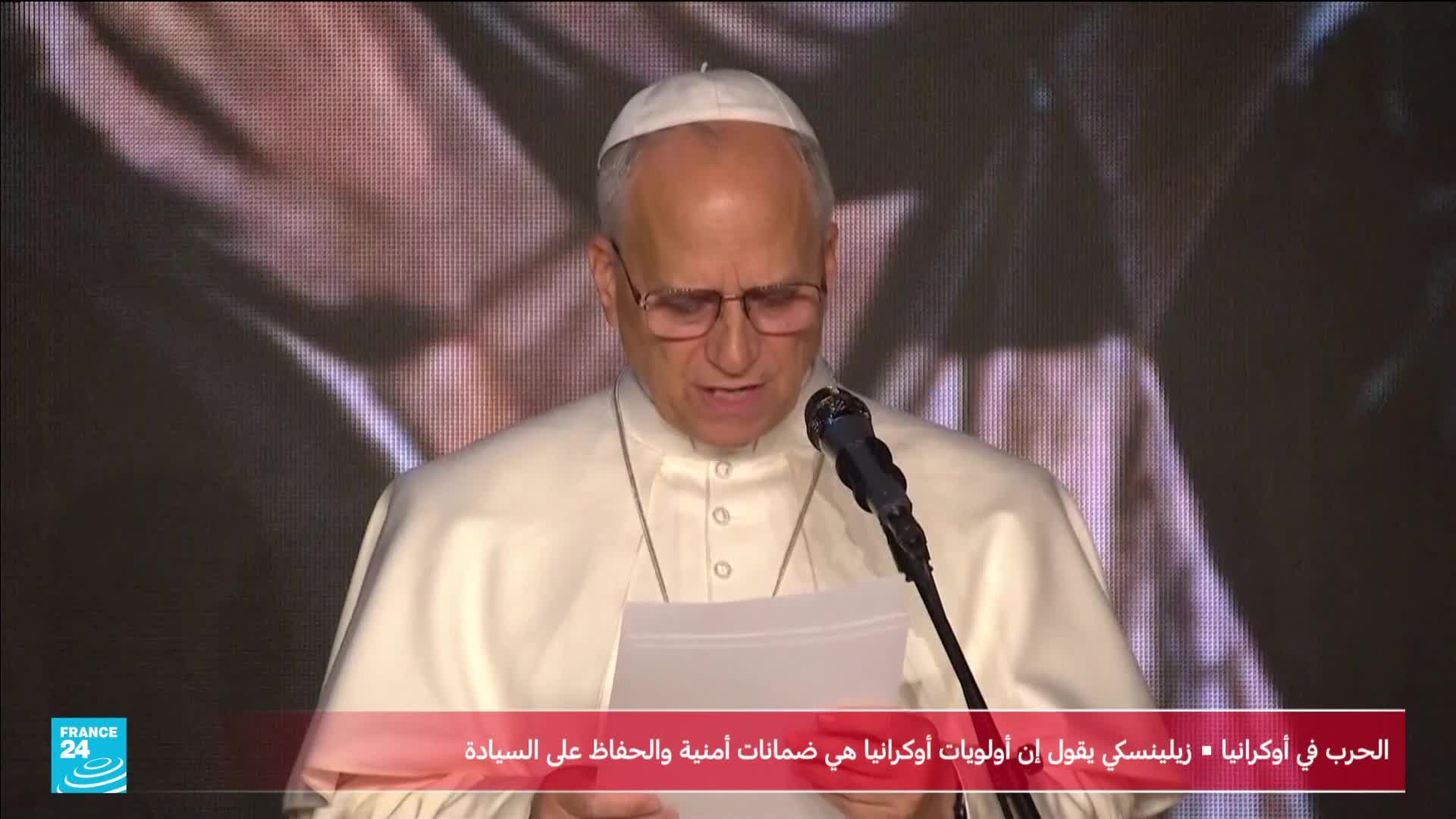 A man in a white papal outfit, wearing glasses, reads from a paper held in his hands. The France 24 logo is visible at the bottom left, with Arabic text indicating coverage of the war in Ukraine.
A man in a white papal outfit, wearing glasses, reads from a paper held in his hands. The France 24 logo is visible at the bottom left, with Arabic text indicating coverage of the war in Ukraine.