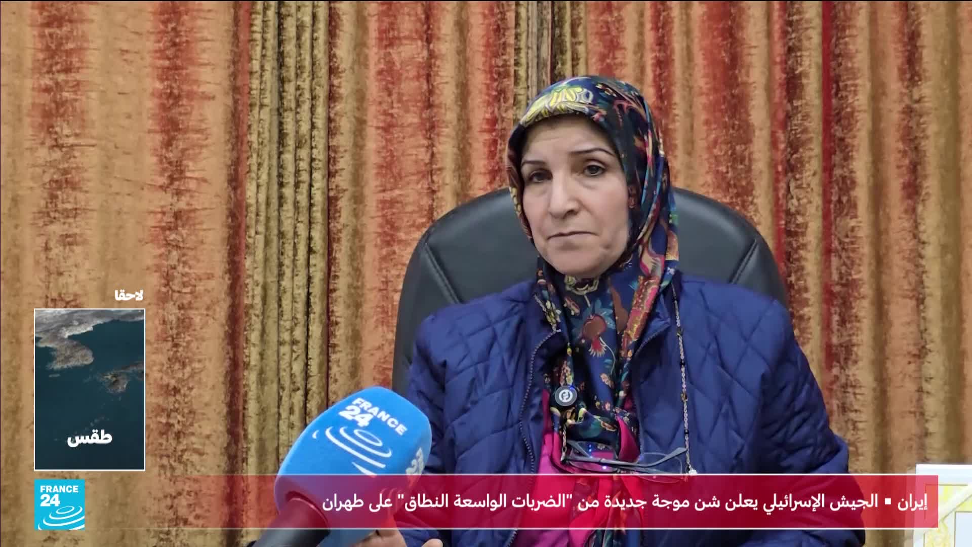 A woman with a patterned headscarf speaks into a France 24 microphone. A small weather graphic appears in the lower left corner of the screen.